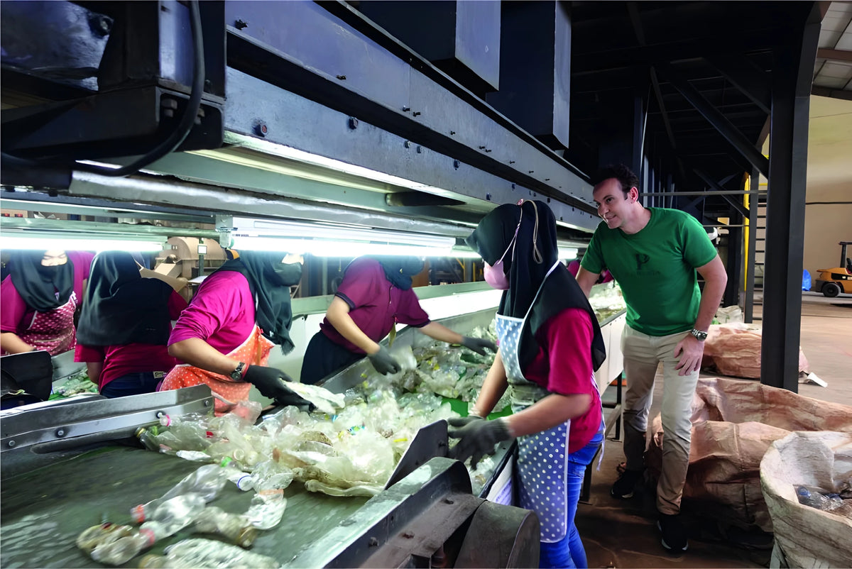 Founder Bruno Hasson at a plastic recycling plant with sorting-line workers